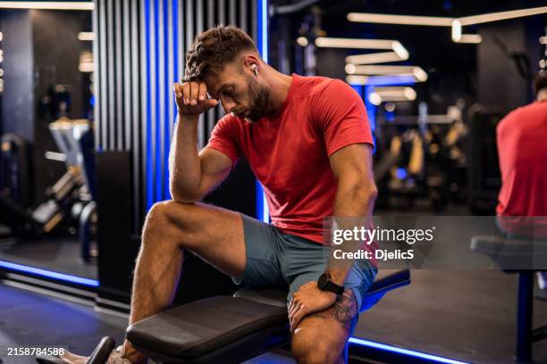erschöpfter athletischer mann, der sich von einem training im fitnessstudio ausruht. - bodybuilding stock-fotos und bilder