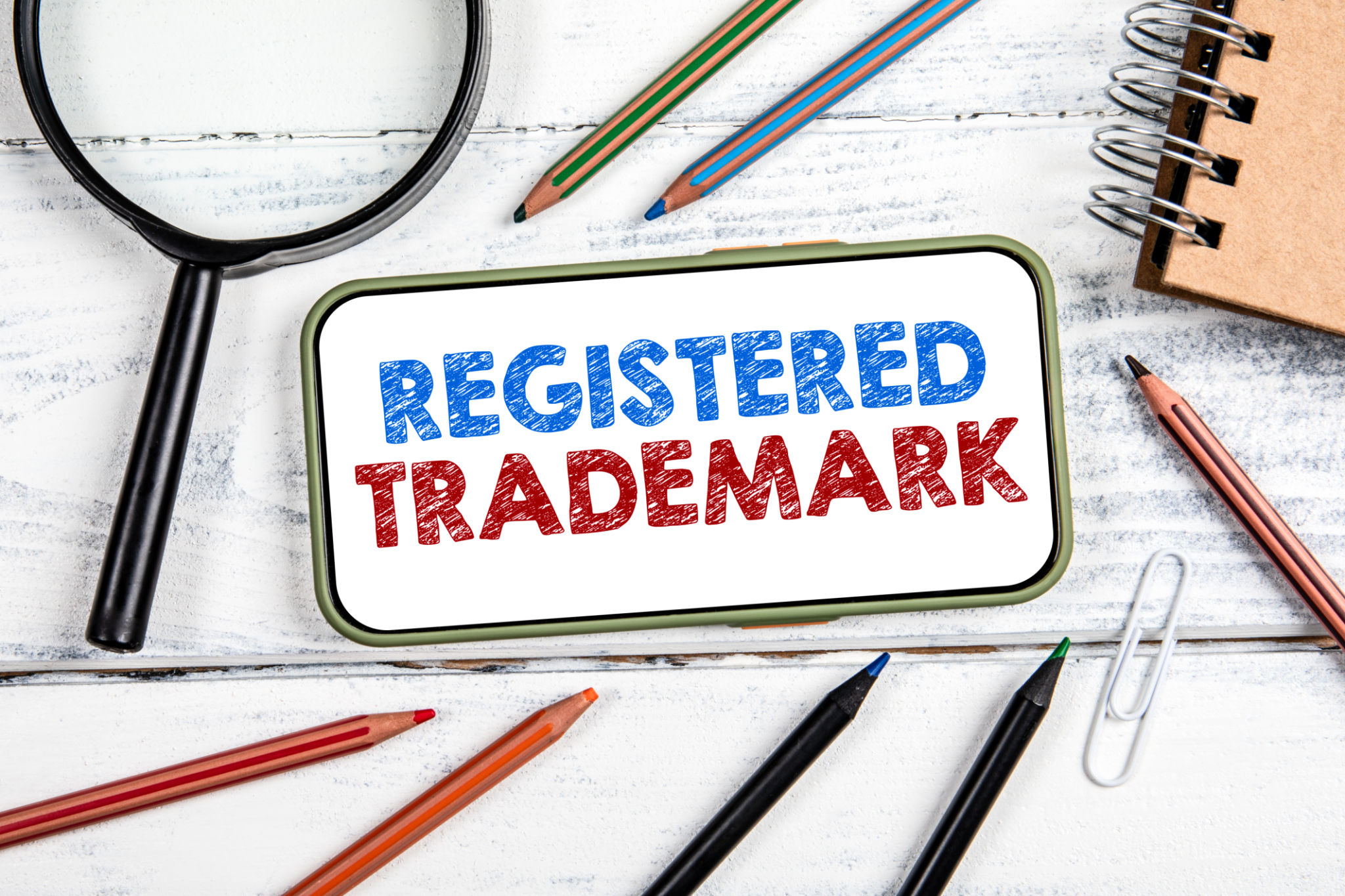 Registered Trademark Concept. Mobile phone on white wooden office table Registered Trademark Concept. Mobile phone on white wooden office table