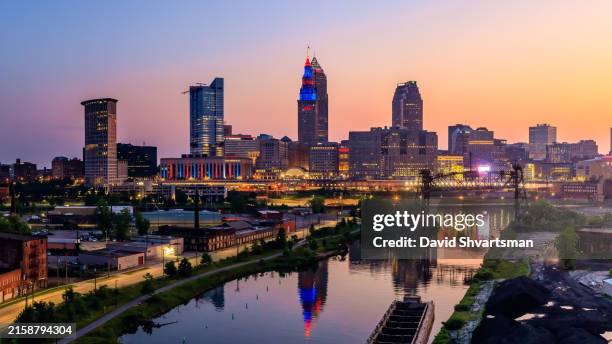 a view of cleveland's skyline from the south in the early morning, with the tower city building illuminated in red and blue - cleveland, ohio, usa. - rock and roll hall of fame cleveland stock-fotos und bilder