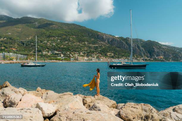 a woman with a yellow beach towel standing near the yacht on the french riviera - saint tropez stock-fotos und bilder