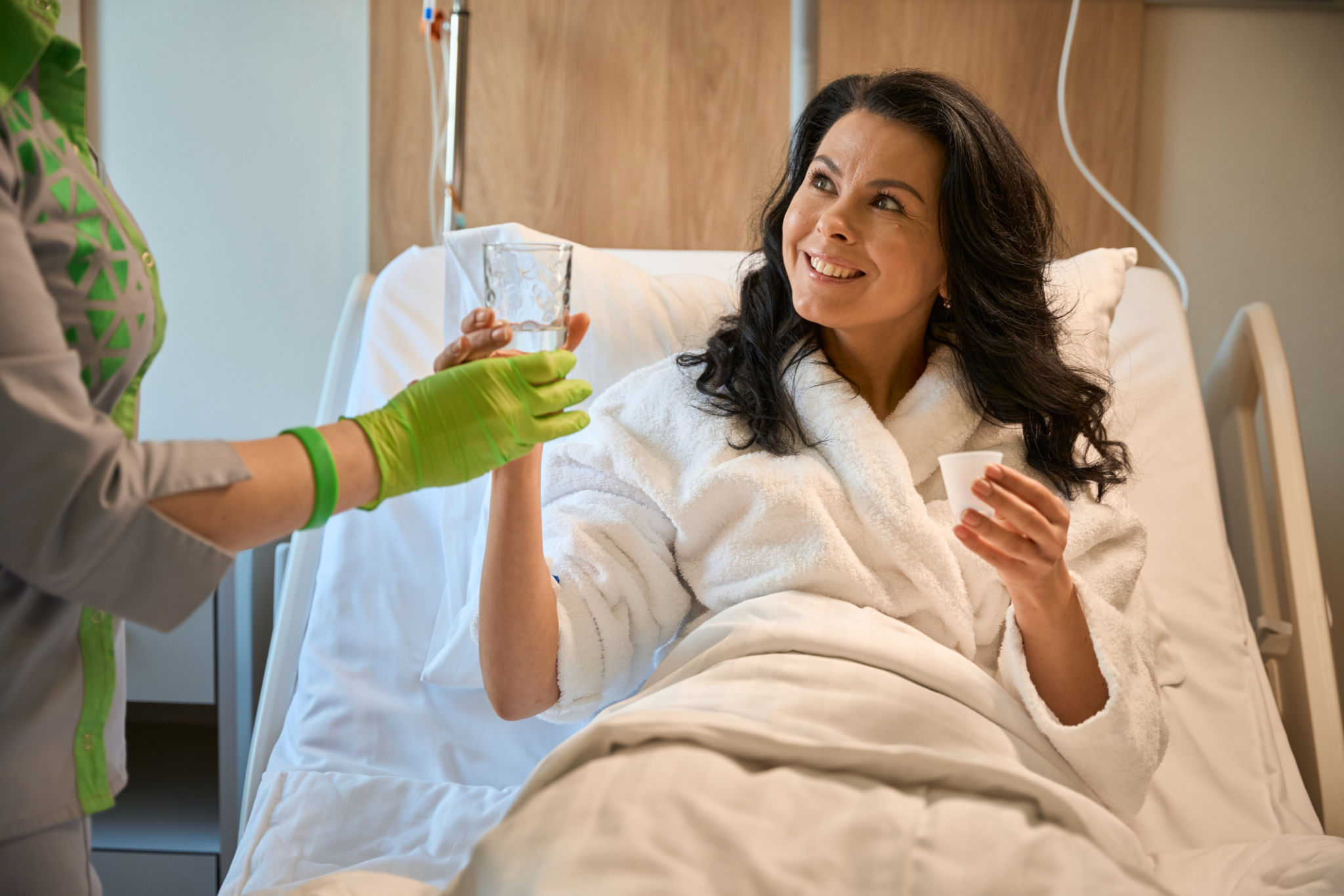 Nurse gives the patient a glass of water Nurse gives the patient a glass of water