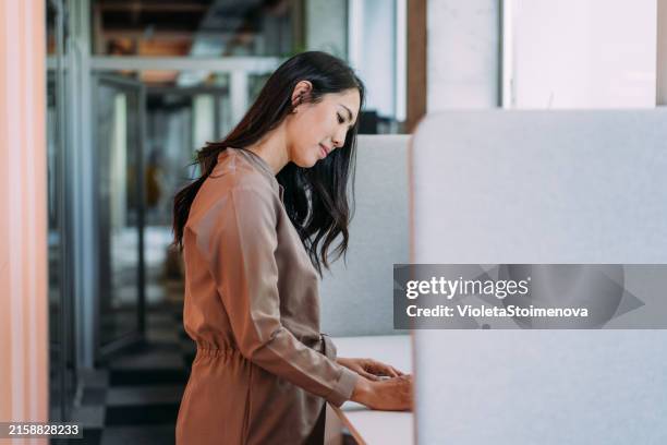 businesswoman working at ergonomic standing workstation. - standing desk stock pictures, royalty-free photos & images