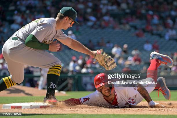 Zach Neto of the Los Angeles Angels beats the tag by Tyler Soderstrom of the Oakland Athletics on a pick off attempt in the eighth inning at Angel...