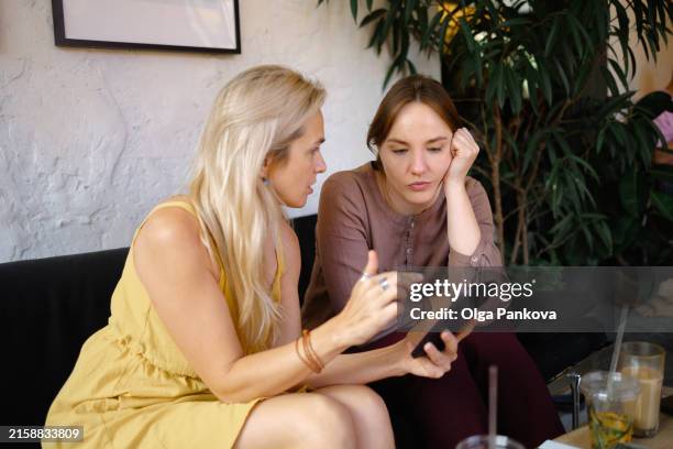 two women are having a serious conversation using phone - gossip stock pictures, royalty-free photos & images