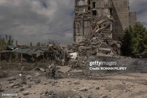 Local resident pushes a bicycle past a destroyed residential building following shelling in the town of Toretsk, eastern Donetsk region, on June 25...