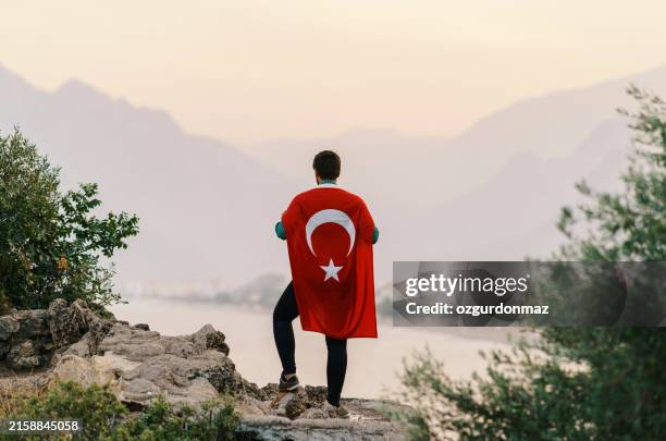 proud young man covered with turkish flag , standing on the top of the hill at sunset - turkish people stock pictures, royalty-free photos & images