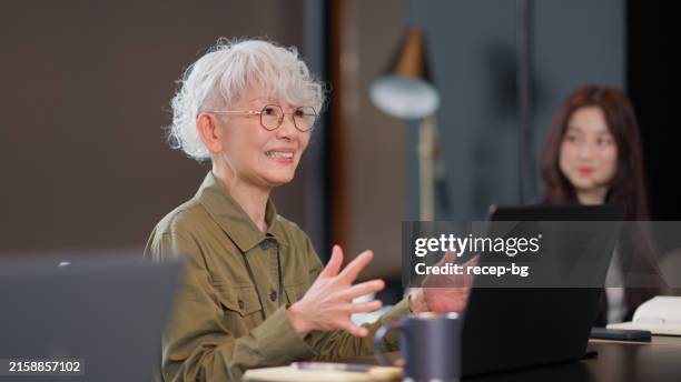 femme d’affaires asiatique âgée parlant lors d’une réunion d’affaires et collaboration dans un bureau moderne - retraités qui travaillent photos et images de collection