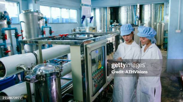 diligent asian quality control water purification process team analyzing data on tablet in a high-tech manufacturing facility - bottling plant stock pictures, royalty-free photos & images