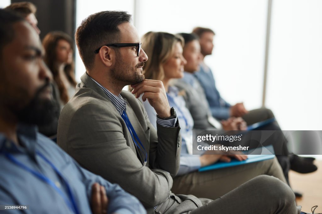 Smiling male entrepreneur with his colleagues on education event in board room.