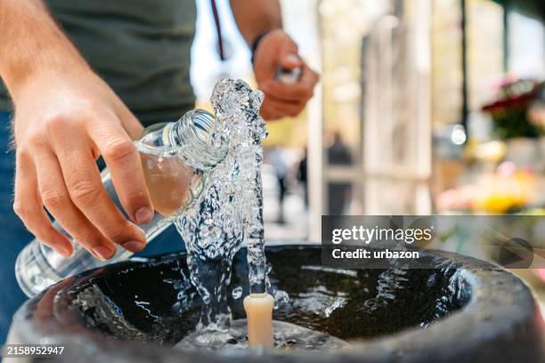 mid-adult man refiling his reusable water bottle on the drinking fountain in yerevan in armenia - fontein stockfoto's en -beelden