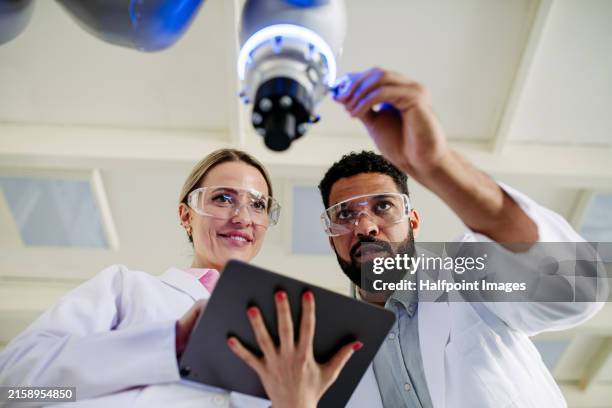 two robotic engineers, scientists checking data in tablet after successful experiment in modern robotics laboratory. concept of robotics, engineering and computer science. - scientists working together stock pictures, royalty-free photos & images