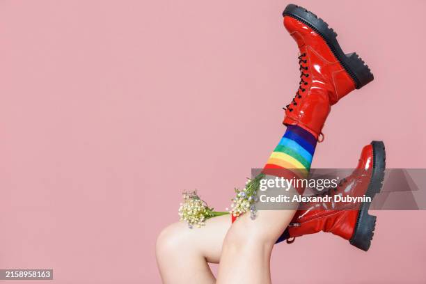 female legs in colored rainbow socks and red shoes from which flowers grow on a pink background. shoe sales concept. - zapatos de colores fotografías e imágenes de stock