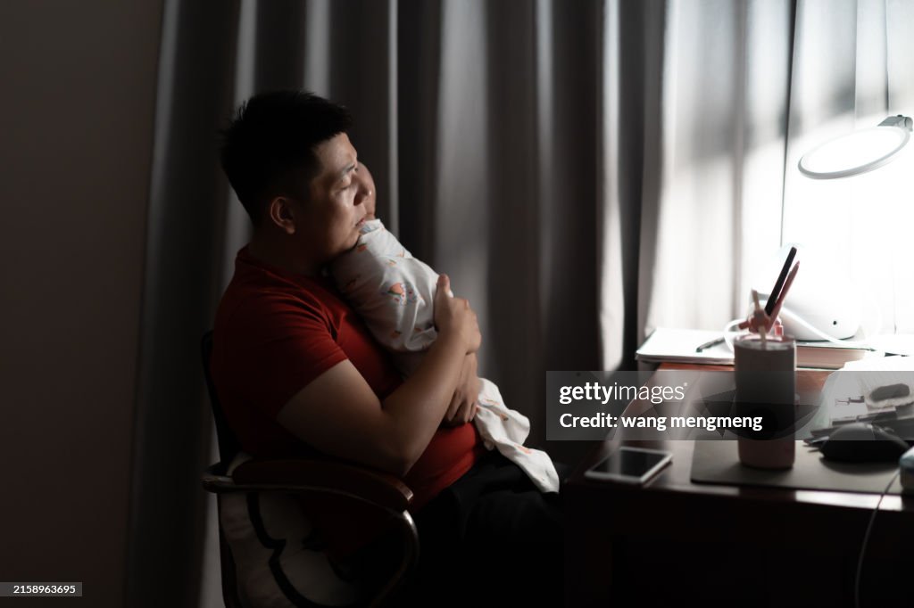 A young novice father wearily hugged his baby