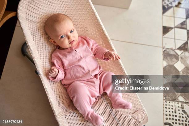a cute baby in a pink outfit peacefully resting in a wicker bassinet, creating a cozy and domestic scene - un seul bébé fille photos et images de collection