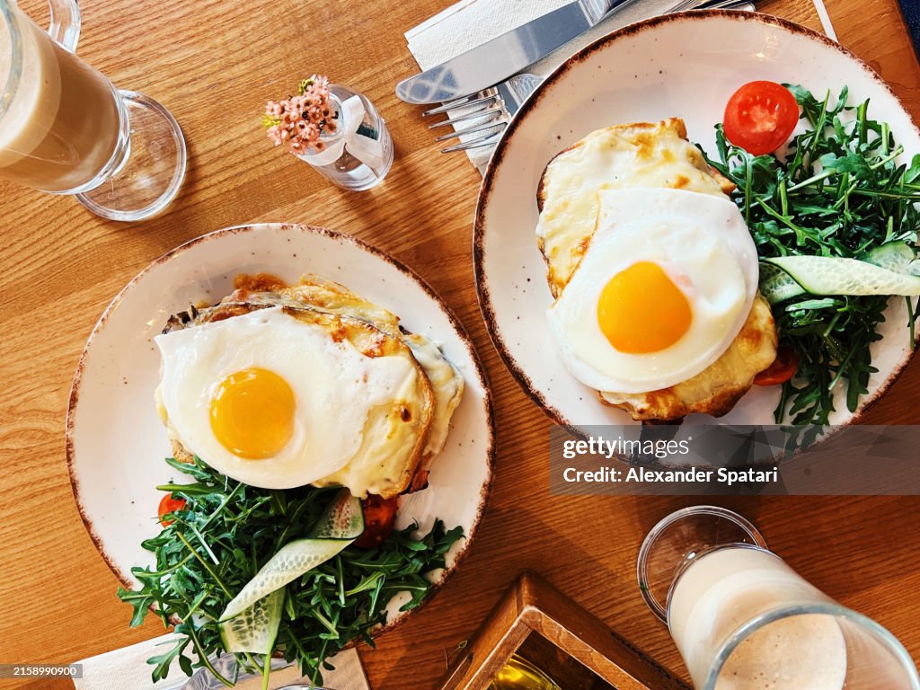 Croque Madame cheese sandwich with fried eggs served for breakfast in a cafe