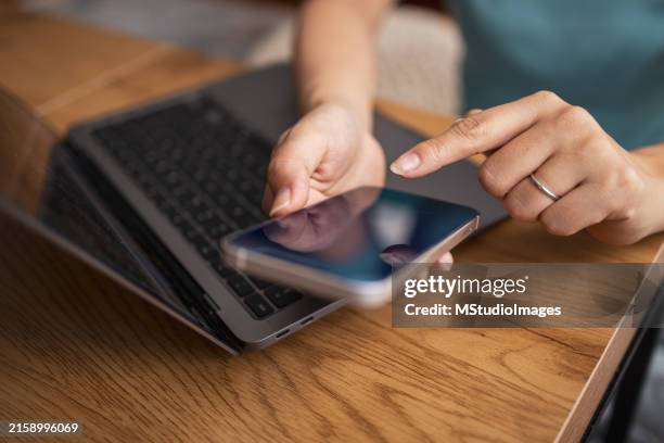 nahaufnahme einer asiatischen frau mit smartphone und laptop. - miteinander verbunden stock-fotos und bilder