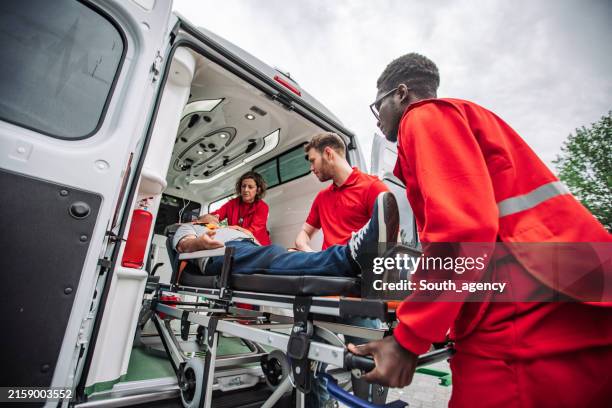 paramedics providing medical assistance loading patient into ambulance - pessoal de ambulância imagens e fotografias de stock