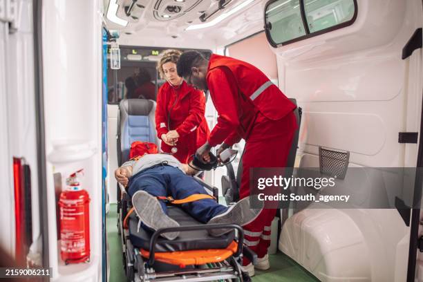 paramedics providing first aid to patient lying on stretcher in ambulance - stretcher stock pictures, royalty-free photos & images