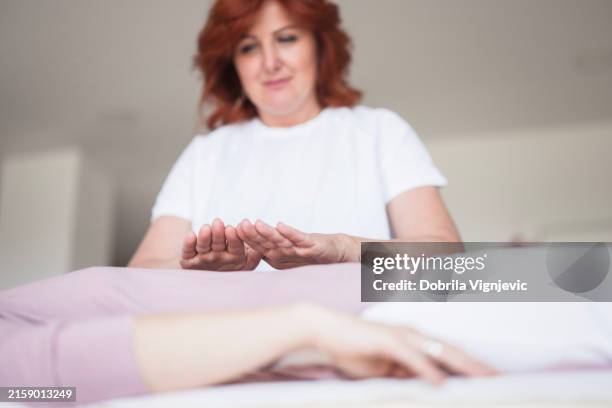 terapeuta de reiki con ambas manos en el cuerpo de un paciente - reiki fotografías e imágenes de stock