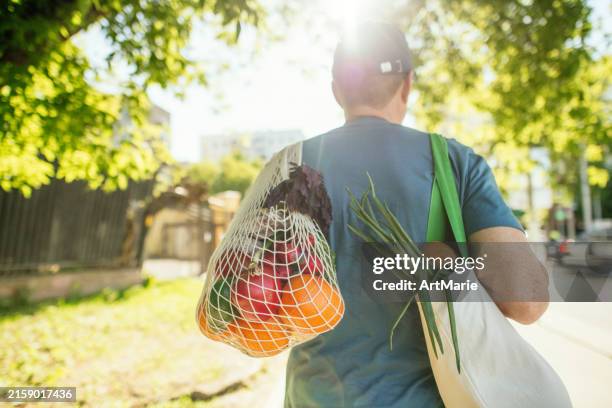 senior man carrying fruits and vegetables in reusable shopping bag and mesh bag, environment conservation and sustainability concept - herbruikbare tas stockfoto's en -beelden