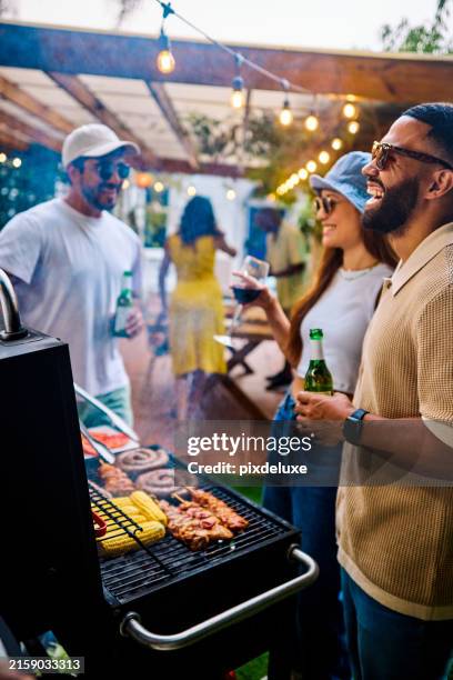 friends laughing and grilling food at an outdoor barbecue party. social gathering with food and drinks. summer celebration concept. - utegrillat bildbanksfoton och bilder