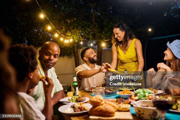 familie und freunde essen an einem tisch im freien unter lichterketten am pool. abendliches geselliges beisammensein mit essen und getränken. konzept für sommerfeste. mittlere aufnahme. - grillfest stock-fotos und bilder