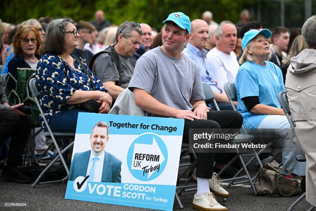 Supporters wait for Reform UK leader Nigel Farage to speak during an ...