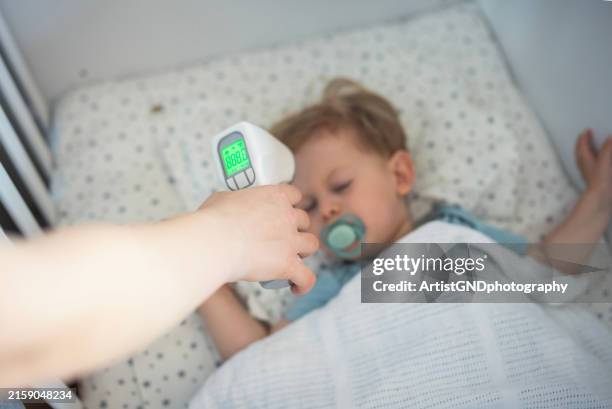 checking child's temperature while sleeping. - infrared thermometer stock pictures, royalty-free photos & images