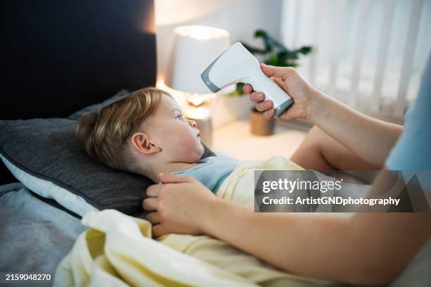 worried mom checking toddler's temperature. - infrared thermometer stock pictures, royalty-free photos & images