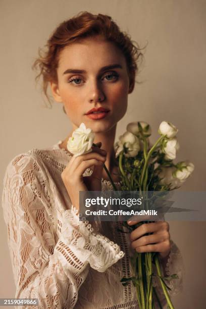 elegant woman holding white flowers in soft lighting - kanten jurk stockfoto's en -beelden