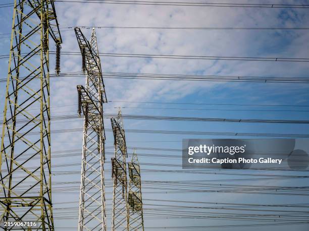 electricity pylons stretching across a cloudy sky - elnät bildbanksfoton och bilder