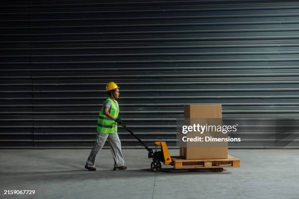 african-american female worker pushing a pallet jack - work boot stock pictures, royalty-free photos & images