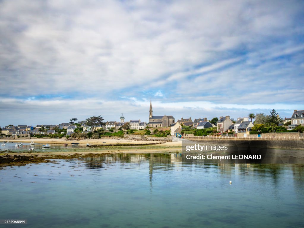 View of the quays of the Batz Island (Île-de-Batz) at low tide with the Notre-Dame-du-Bon-Secours catholic church, a beach and Breton houses, Finistère (Finistere) - Bretagne (Brittany) - Western France.