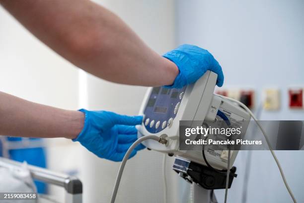 a healthcare professional is operating a medical device with gloved hands inside a clinical setting - medical equipment stock pictures, royalty-free photos & images