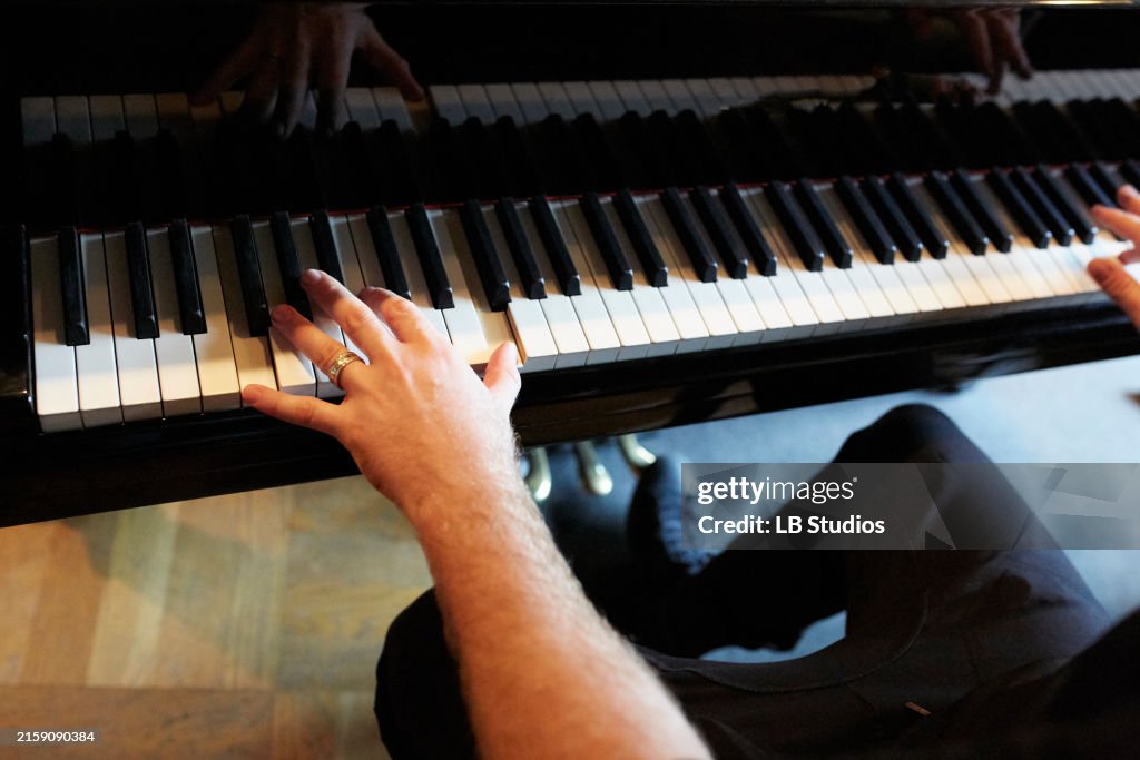 Male pionist sitting at a classic black piano playing