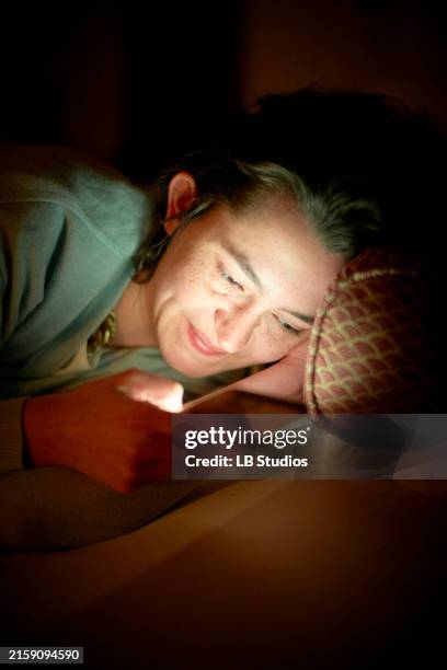 a woman is resting her head on her hand and smiling gently while gazing at a glowing light source, which provides a warm ambiance - warm light stock pictures, royalty-free photos & images