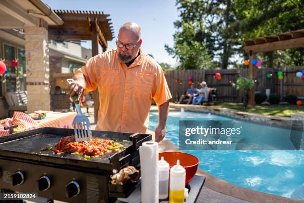 uomo che prepara cibo messicano mentre fa un barbecue a casa con la sua famiglia - griglia per barbecue foto e immagini stock