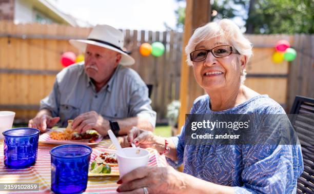 senior adults eating tacos at a family party outdoors - granny eating stock pictures, royalty-free photos & images