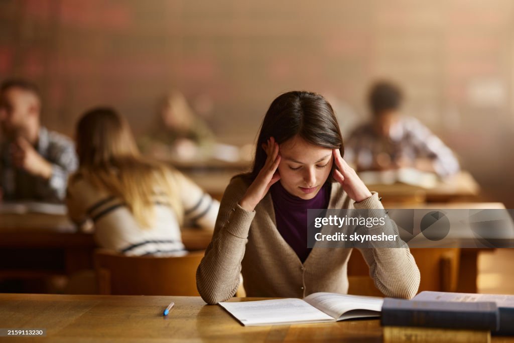 Tired female student learning in library.