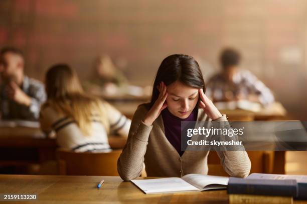tired female student learning in library. - pressão física imagens e fotografias de stock
