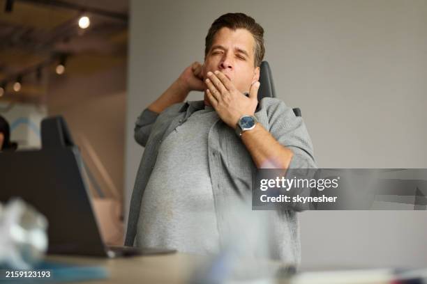 exhausted male programmer yawning in the office. - yawning stock pictures, royalty-free photos & images
