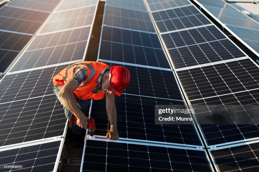 Technician installing solar panel on roof of a building