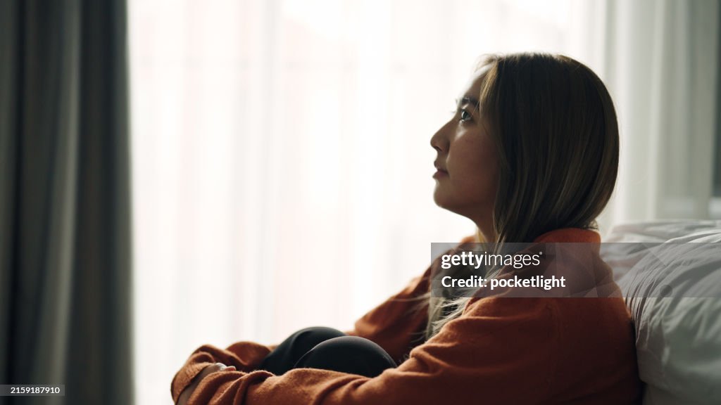 Woman depression hugging herself in bedroom.