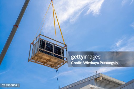 A crane is carrying solar panels onto the factory roof for installation. A crane is carrying solar panels onto the factory roof for installation.