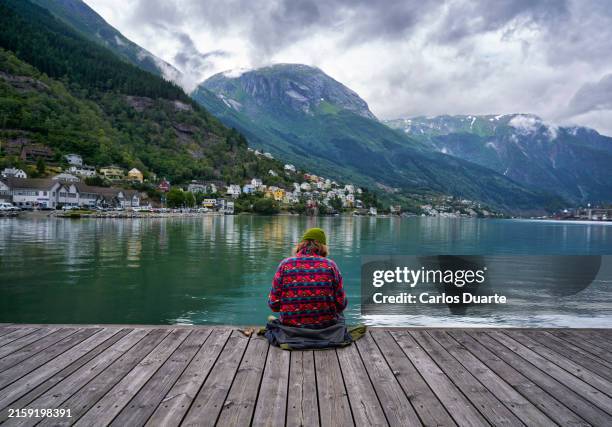 una donna con la schiena ha inviato un messaggio con il suo smartphone in un bellissimo porto su un fiordo in norvegia vicino a oslo - olden foto e immagini stock