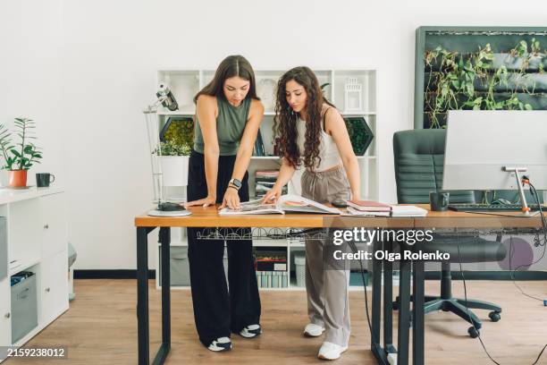interior design selection: two female managers choose interior design from a catalog in the office. - studio di design foto e immagini stock