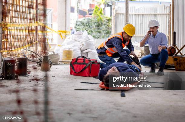 equipo de seguridad que ayuda a un constructor que tiene un accidente en una obra de construcción - accidente fotografías e imágenes de stock