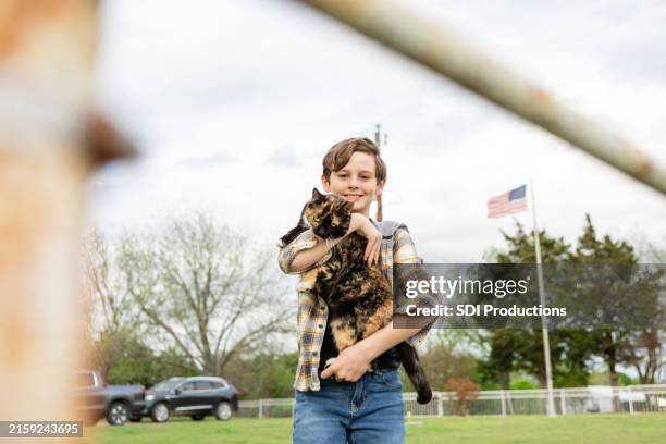 handsome pre-teen boy smiles for the camera while holding his cat - young boy holds united states flag stock pictures, royalty-free photos & images