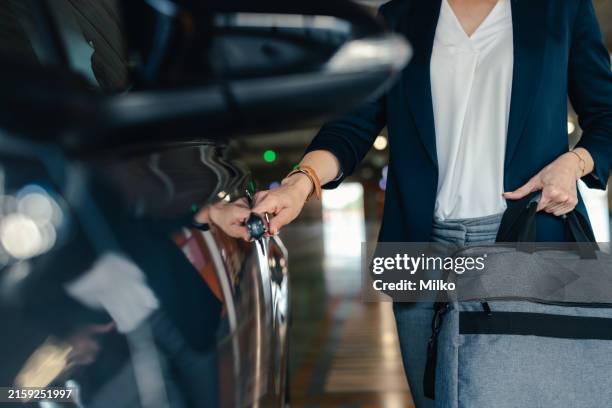 woman opening car door in parking garage - ondergrond stockfoto's en -beelden