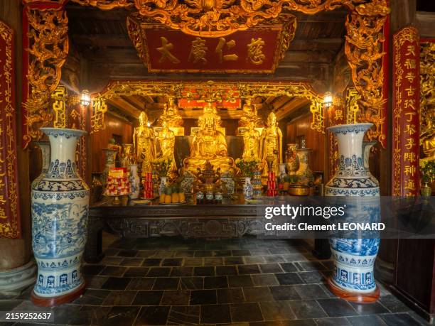 main altar of the phu khong temple, a bouddhist pagoda part of the tràng an scenic landscape complex, an unesco world heritage site, with gold statues of buddha, religious offerings and chinese scripts - trang an - ninh binh - north vietnam. - altar stock pictures, royalty-free photos & images